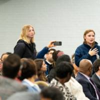 three people standing in line to ask question at microphone